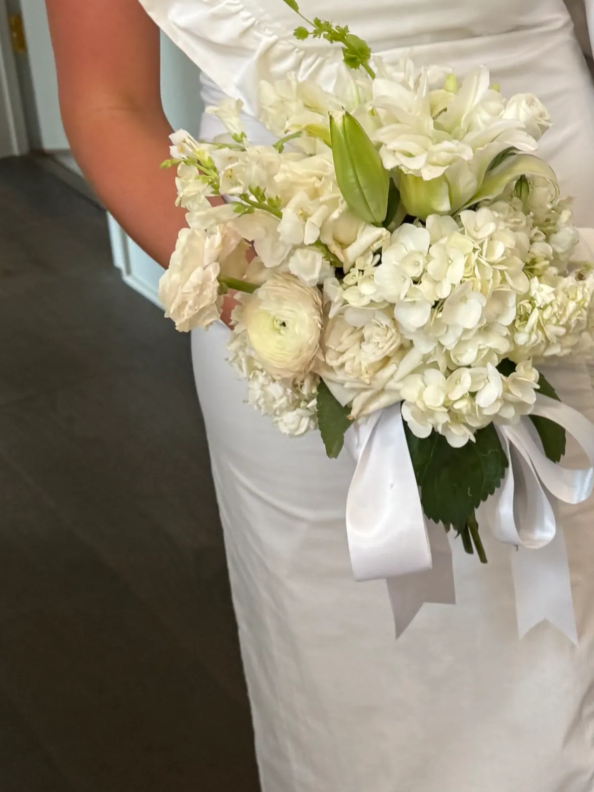 Hand-tied bouquet of white lisianthus, stock and calla lilies tied with a wide white satin ribbon